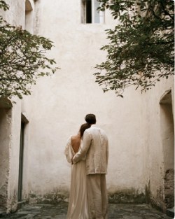 Couple embracing in a sunlit whitewashed courtyard under a tree
