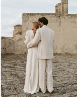 Couple in white embracing beside old stone walls