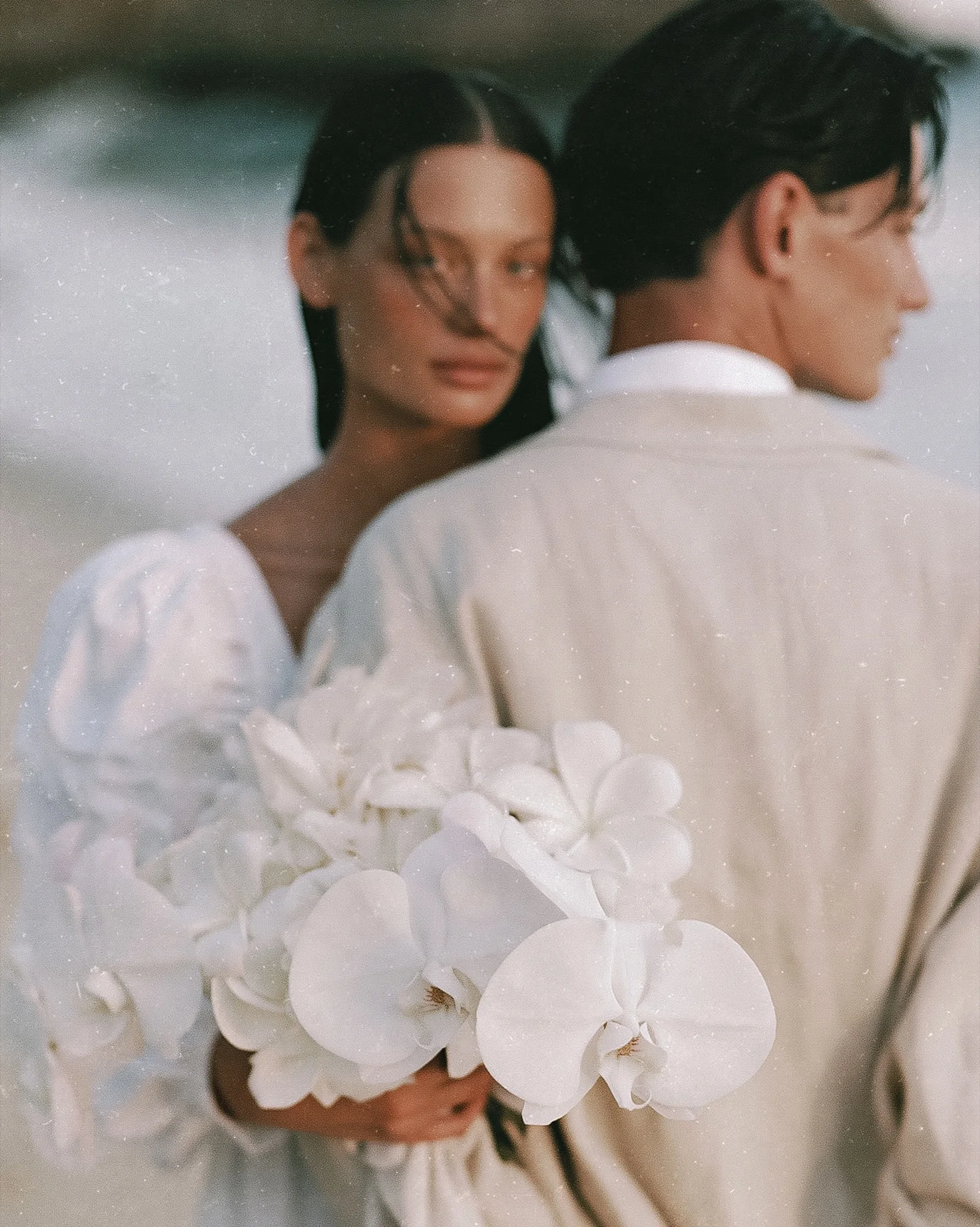 Couple holding white orchids by the sea