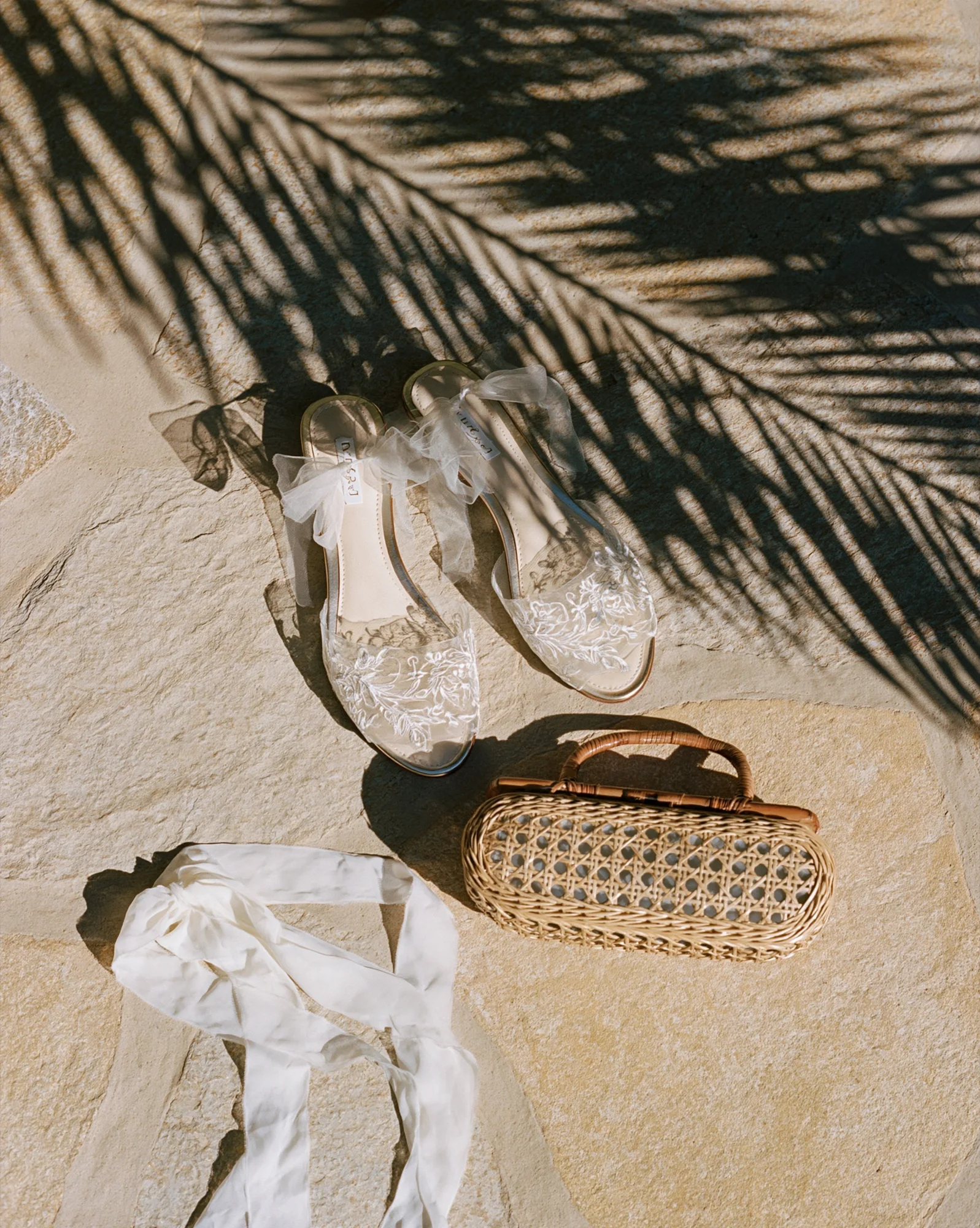 Bridal sandals and rattan clutch on sand