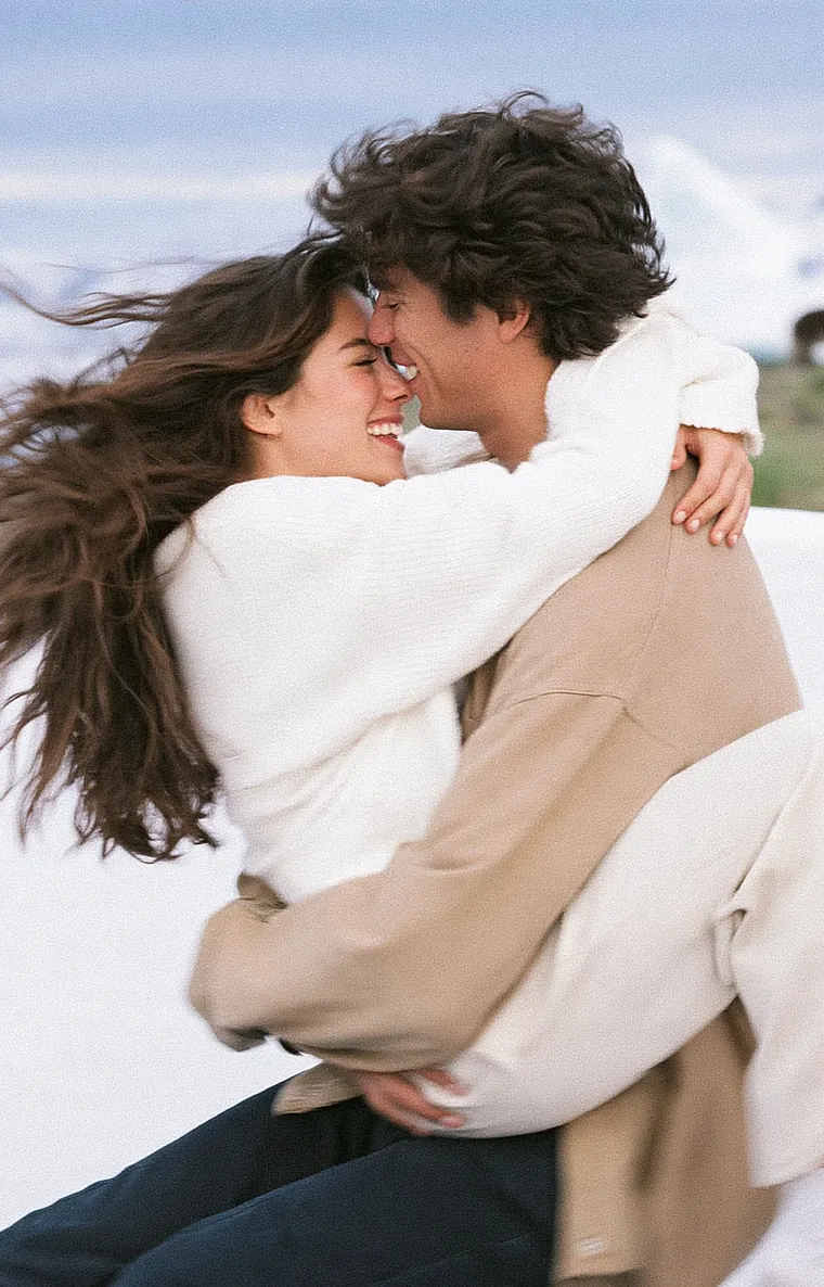 Couple in cream knitwear embracing outdoors under a cloudy sky
