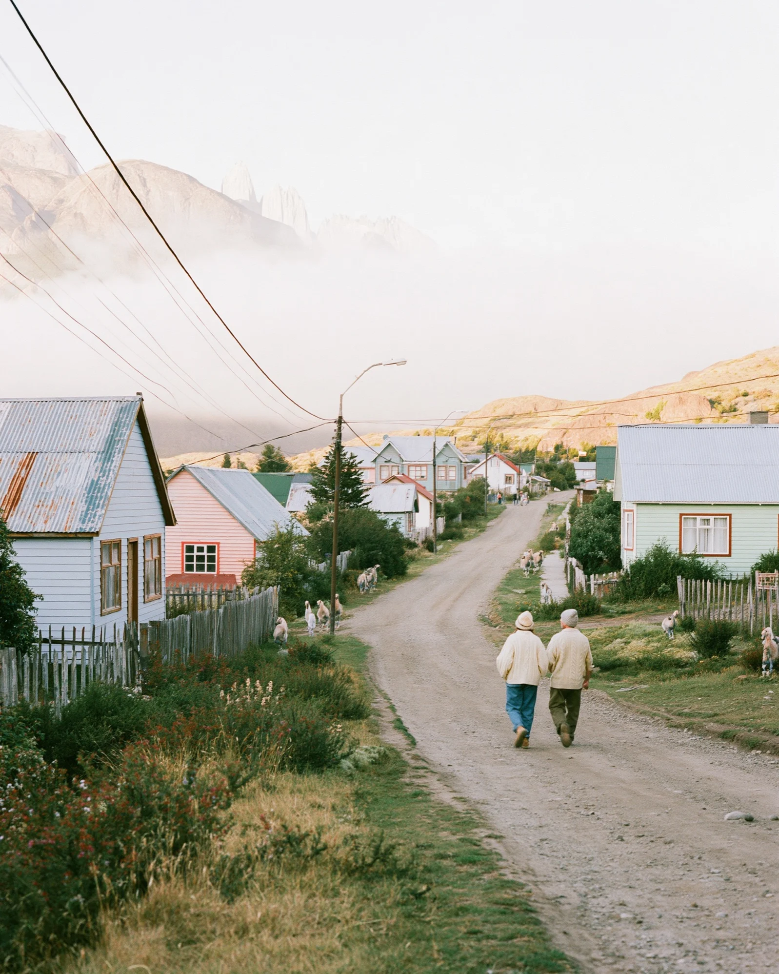 Couple walking down a gravel road through the mountain village of El Chaltén