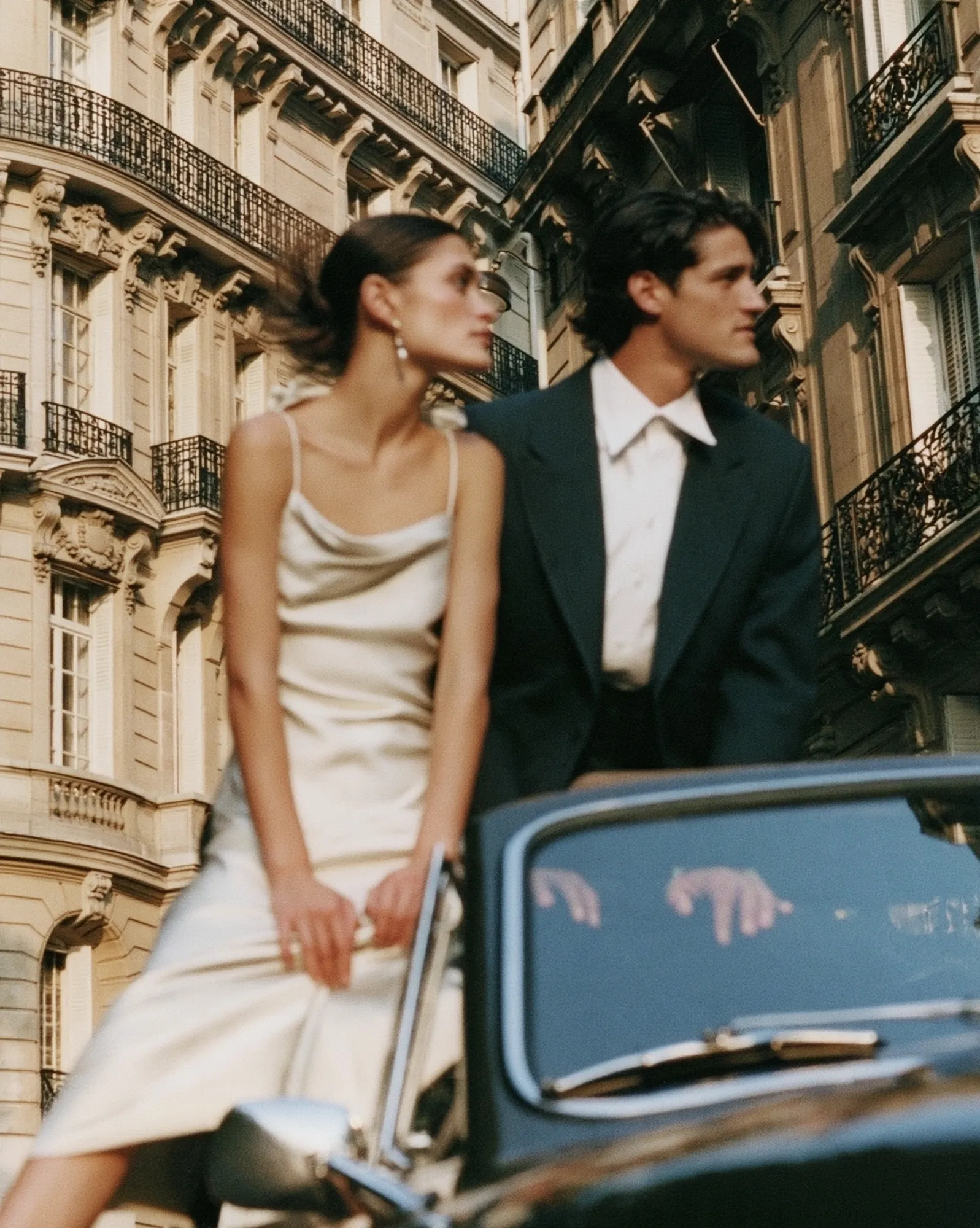Couple posing with a vintage car in front of Haussmann buildings