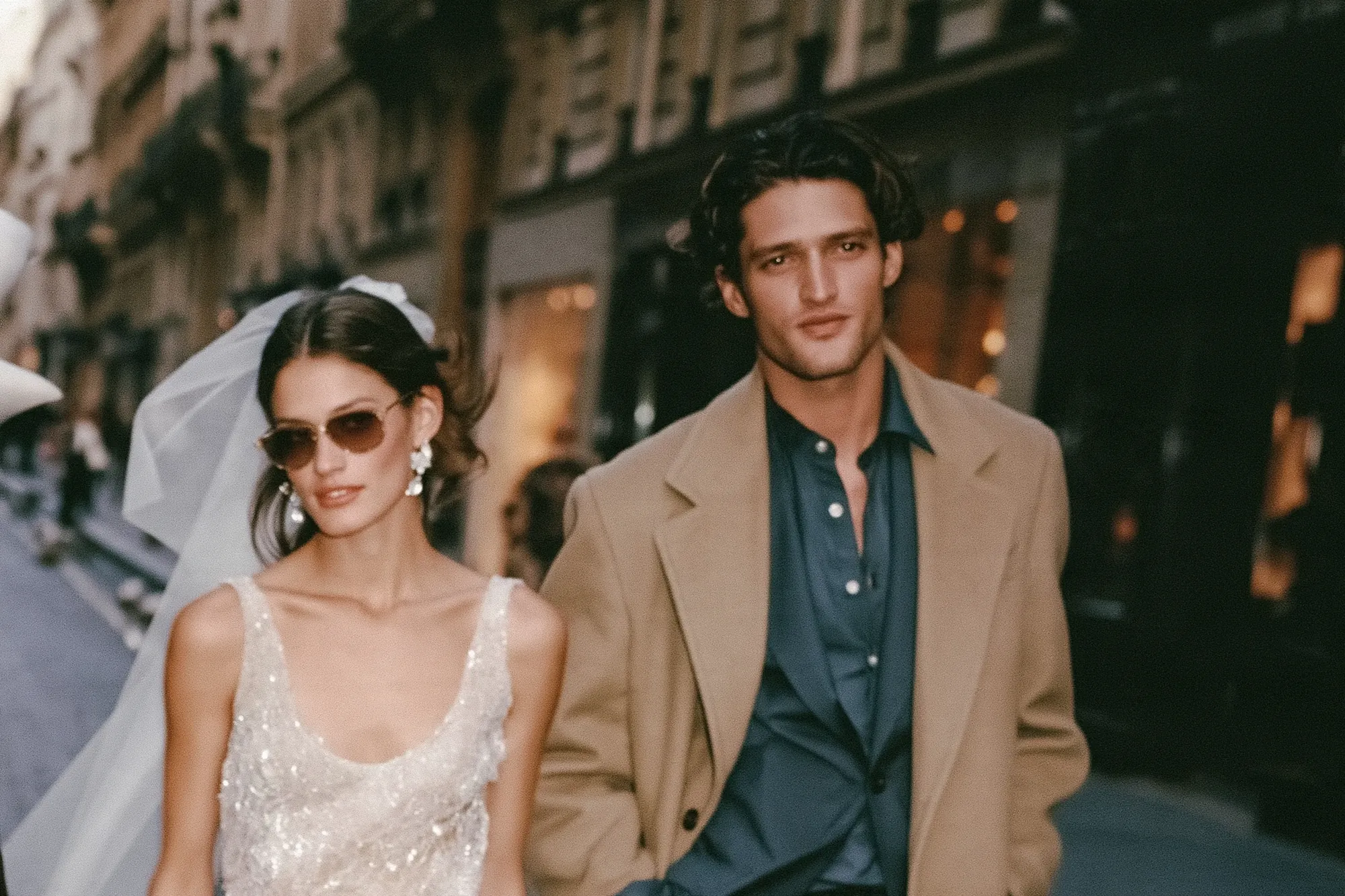 Bride in sunglasses and veil walking with the groom in Paris