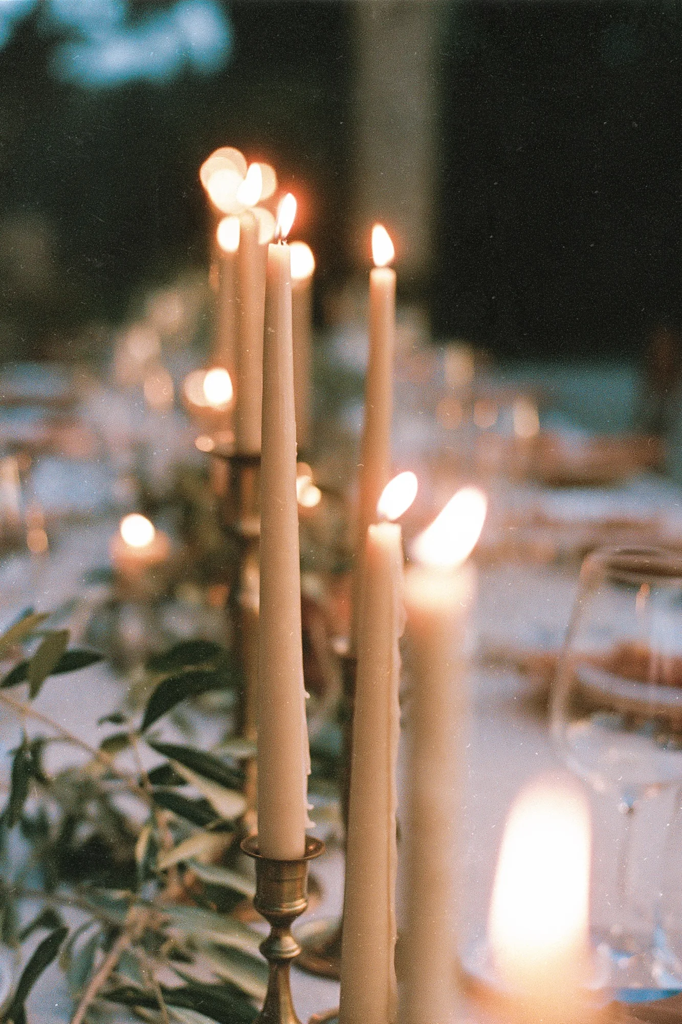 Tall taper candles glowing on the wedding dinner table