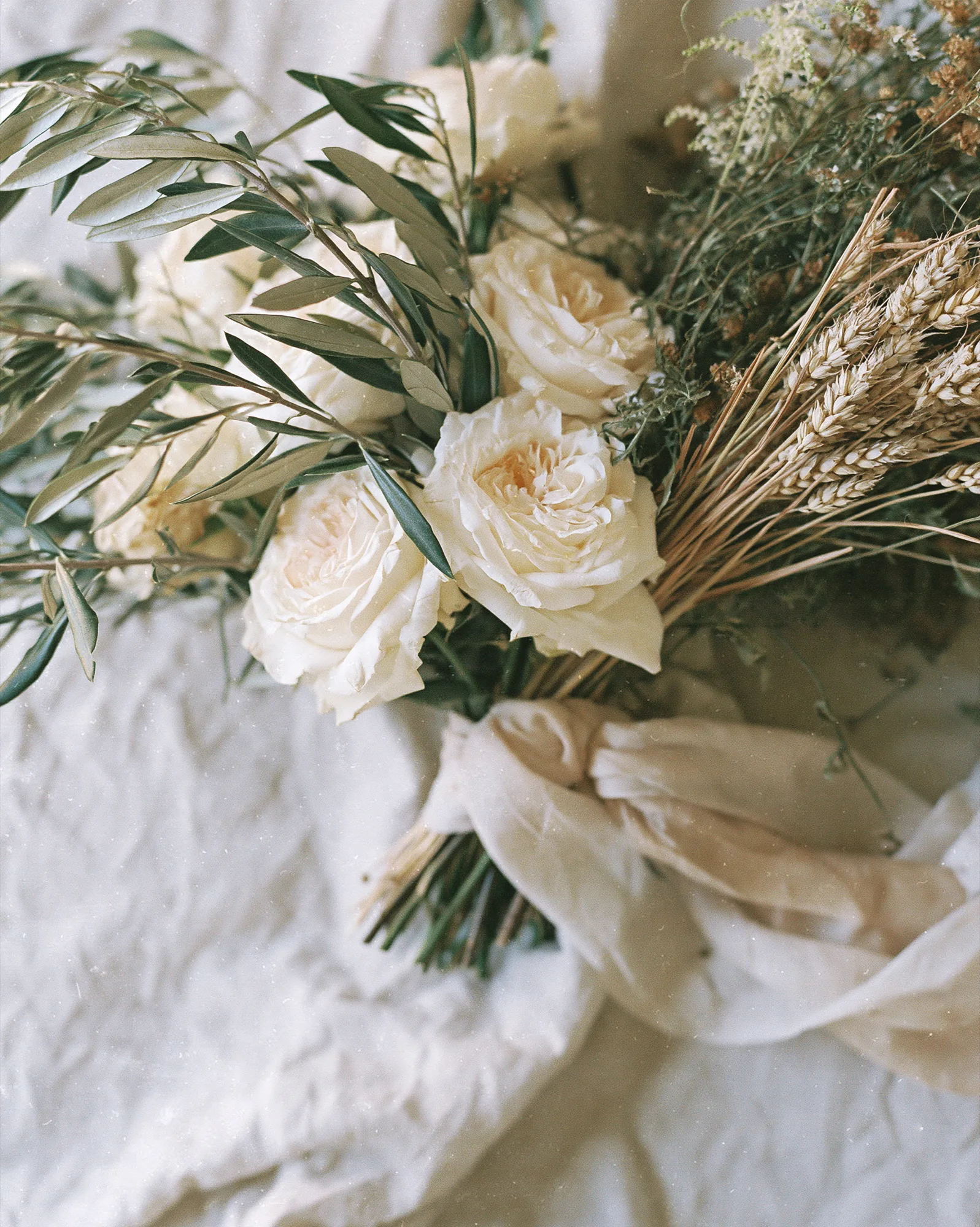 Bridal bouquet of white roses and olive branches on linen