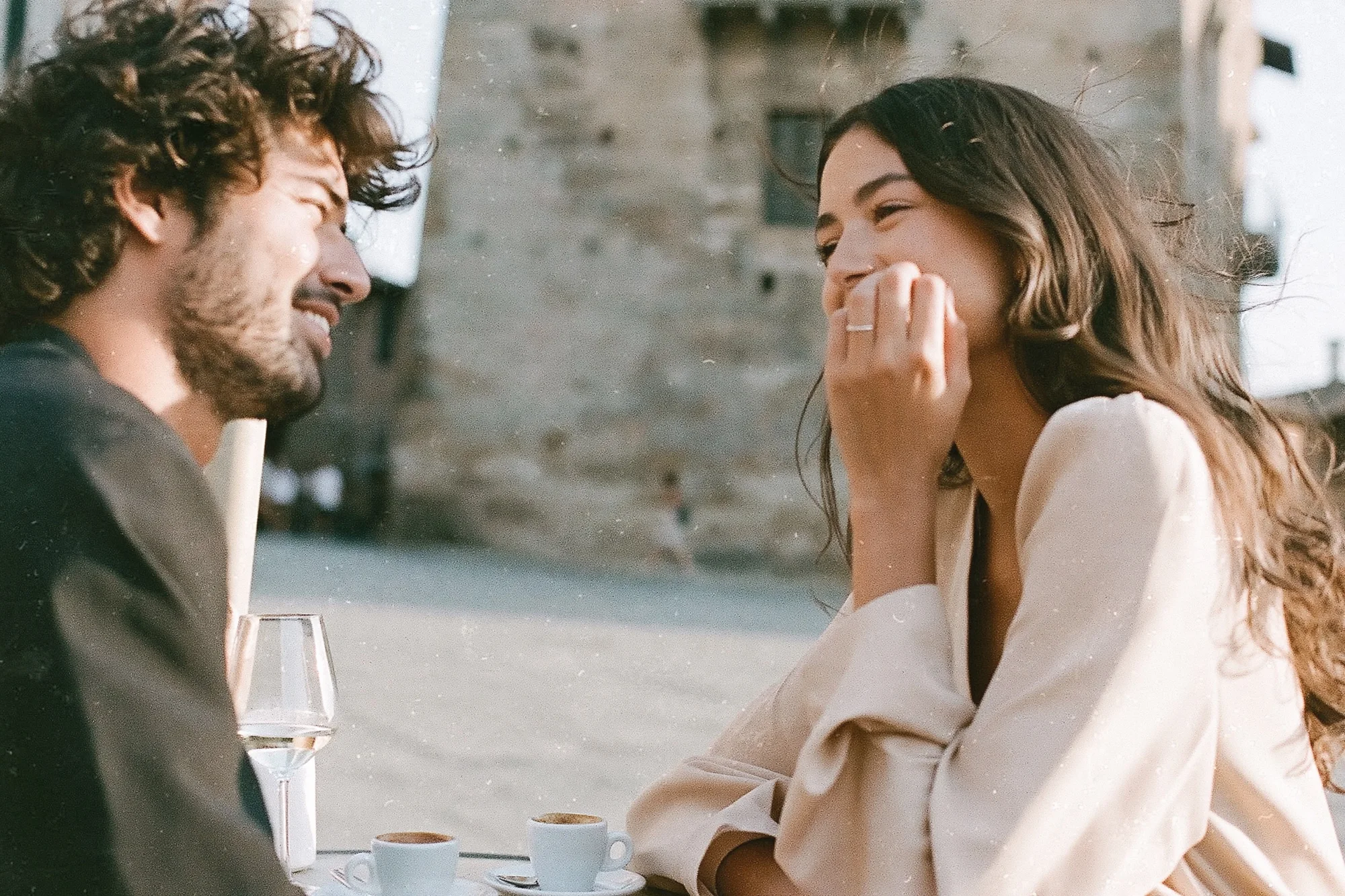 Couple laughing at a café table in a Tuscan village